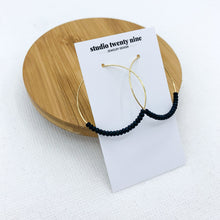 Load image into Gallery viewer, Black beaded gold hoop earrings. Minimalist and lightweight. Small black seed beads are strung on thin 18k gold filled hoops.
