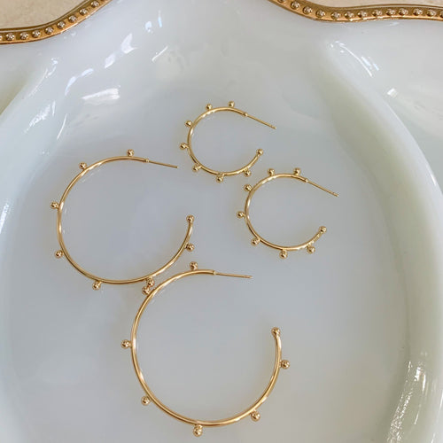 18k gold filled thin hoop earrings with ball stud detail. Open hoop, push back closure. Lightweight, high quality, tarnish resistant. Shown in 2 available sizes - 1 inch and 1.75 inches.