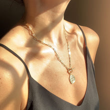Load image into Gallery viewer, 14k gold filled paperclip link chain connected with a front toggle clasp and a rustic gold coin pendant, shown on model. High quality, tarnish resistant. Chain length is customizable.

