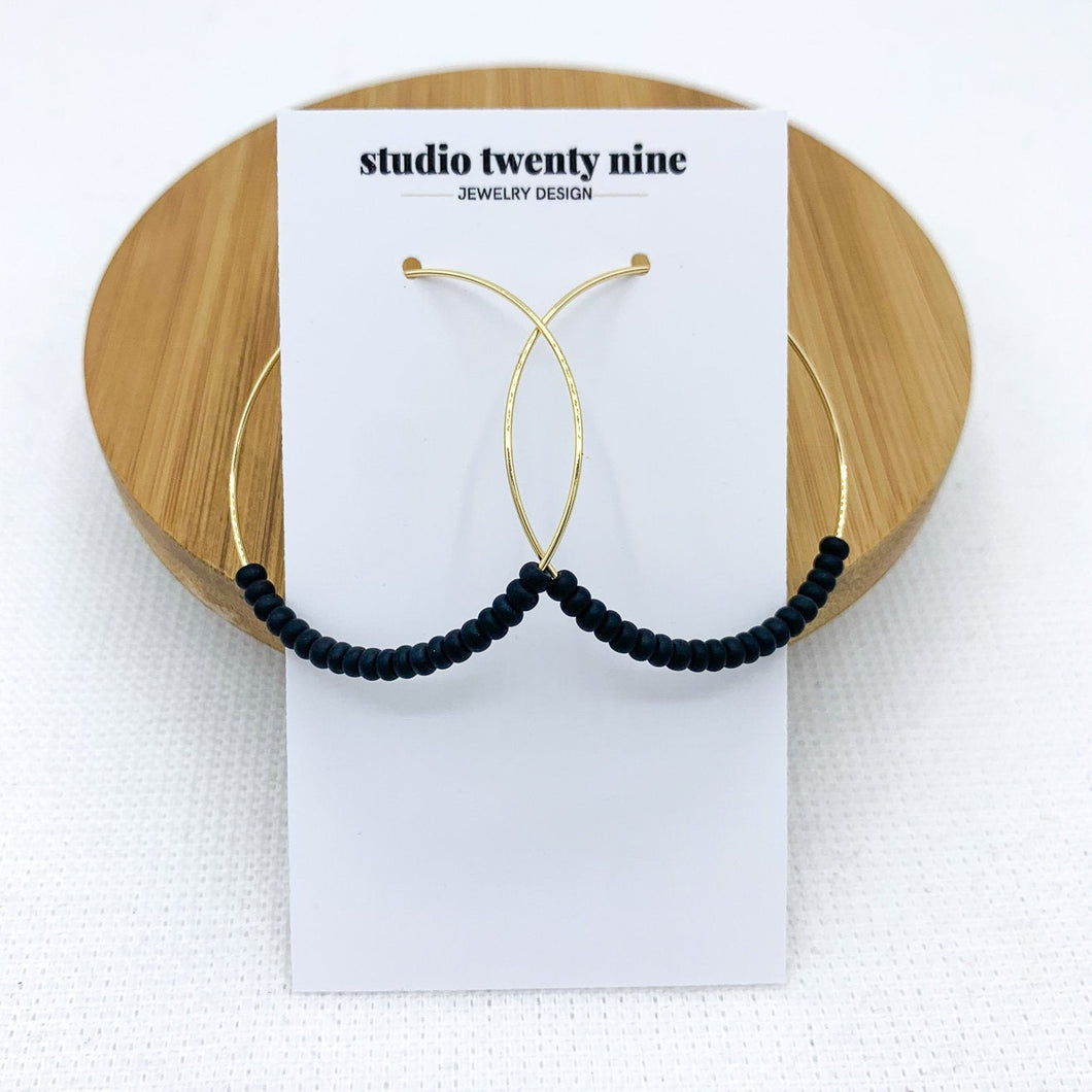 Black beaded gold hoop earrings. Minimalist and lightweight. Small black seed beads are strung on thin 18k gold filled hoops.
