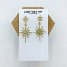 Load image into Gallery viewer, Bold, chic gold starburst CZ dangle earrings with a sparkly style that catches the light in a beautiful way. High quality, hypoallergenic 24k gold plated posts.
